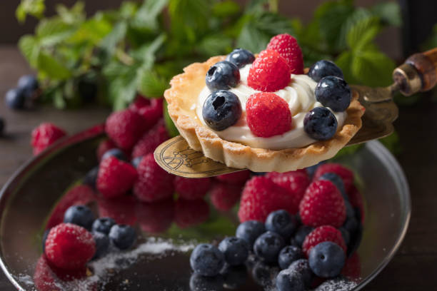 istock Dessert tarts with raspberries and blueberries on a wooden table. 958407832