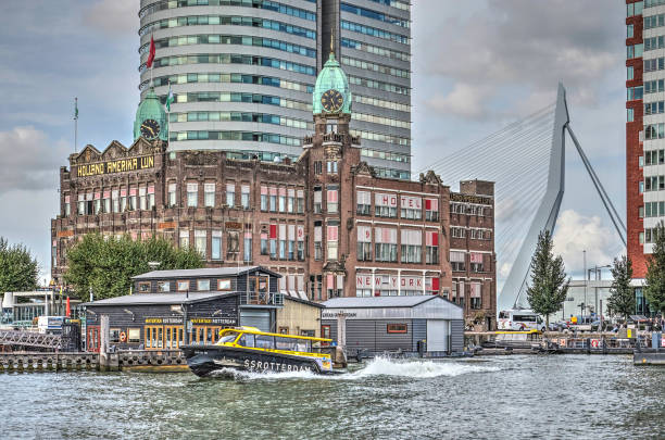 Watertaxi leaving Hotel New York Rotterdam; The Netherlands; September 9; 2017: Watertaxi speeding away from its jetty at Hotel New York on Wilhelminapier, with Erasmus bridge in the background watertaxi stock pictures, royalty-free photos & images