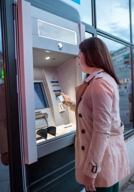 istock young woman inserting a credit card to ATM 958412018