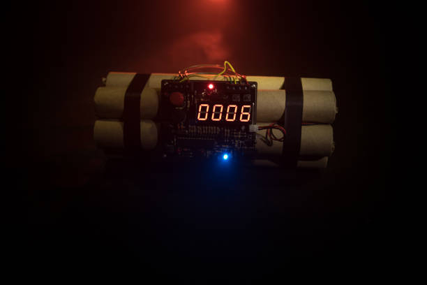 istock Image of a time bomb against dark background. Timer counting down to detonation illuminated in a shaft light shining through the darkness 958412282