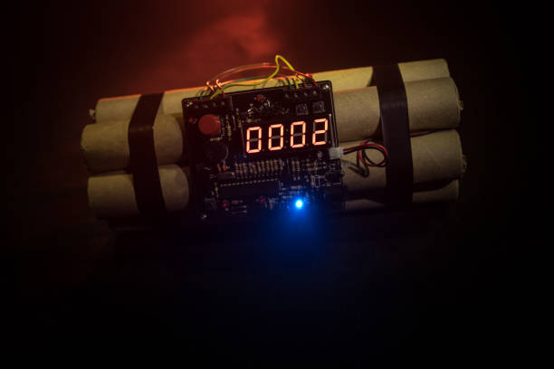 istock Image of a time bomb against dark background. Timer counting down to detonation illuminated in a shaft light shining through the darkness 958412284