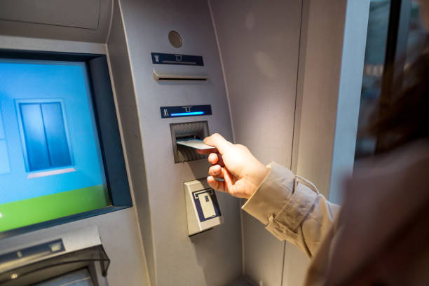 istock young woman inserting a credit card to ATM 958412336