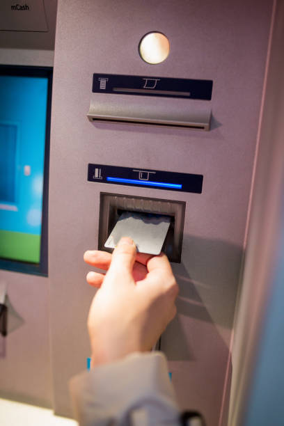 istock young woman inserting a credit card to ATM 958412542