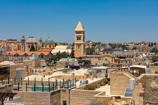 Domes and belfries among typical  stone buildings and rooftops under blue sky in Old City of Jerusalem, Israel.
