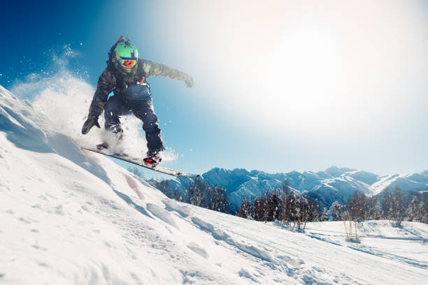 snowboarder salta con tabla de snowboard - snowboarding fotografías e imágenes de stock