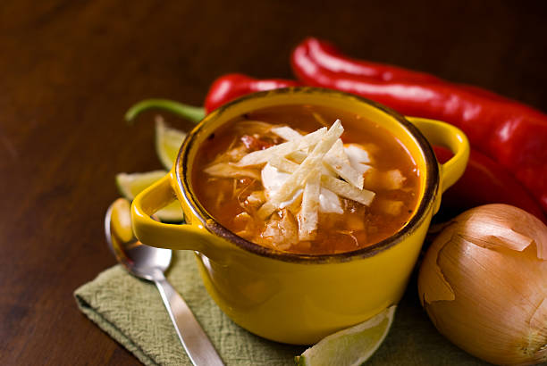 A Mexican tortilla soup in a bowl on a wooden table stock photo