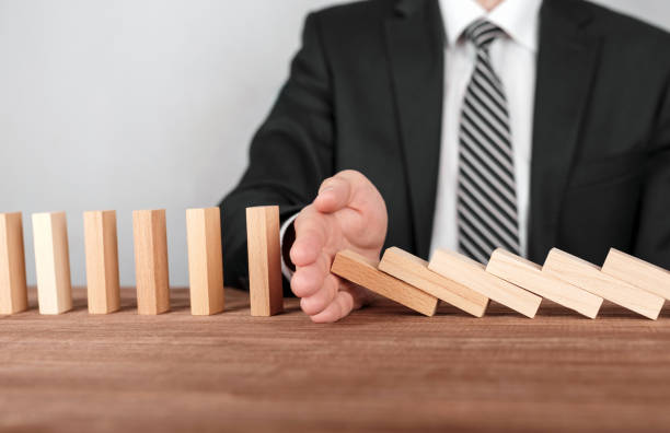 istock Businessman stopping domino effect with his hand. Security and insurance concept 958437726