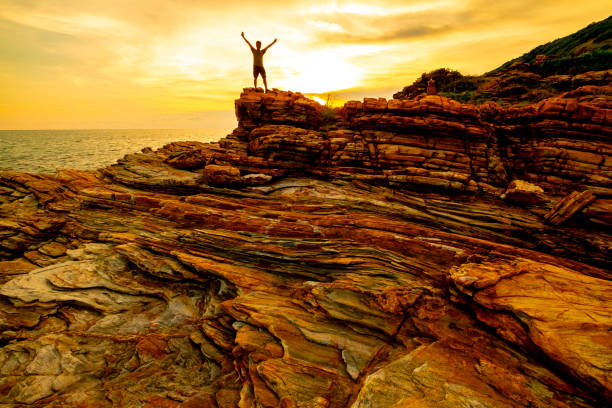 istock one man standing on orange stone and blue sea,background 958456926