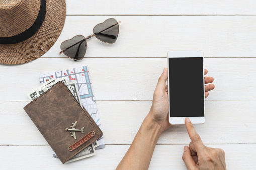 Traveler holding smart phone with passport and map, Travel concept