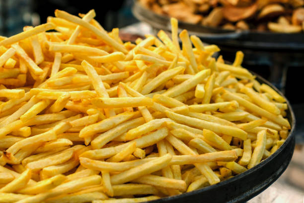 produção de batatas fritas. panela de batata-doce fresca frita. - gold potato - fotografias e filmes do acervo