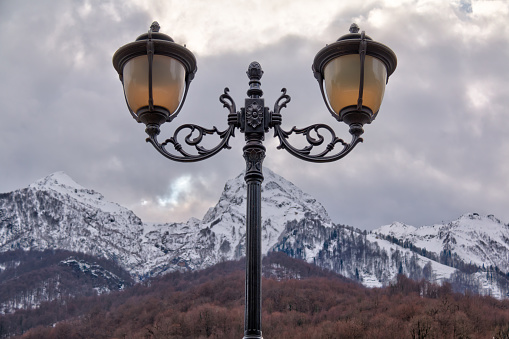 Streetlight on the background of mountain covered with snow in winter day closeup, Krasnaya Polyana, Sochi, Russia