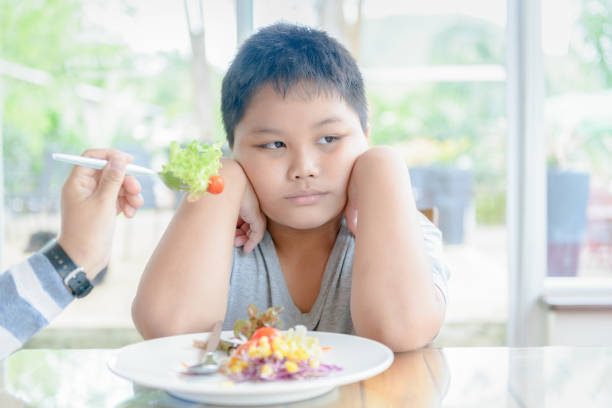 istock obese boy with expression of disgust against vegetables 958469094