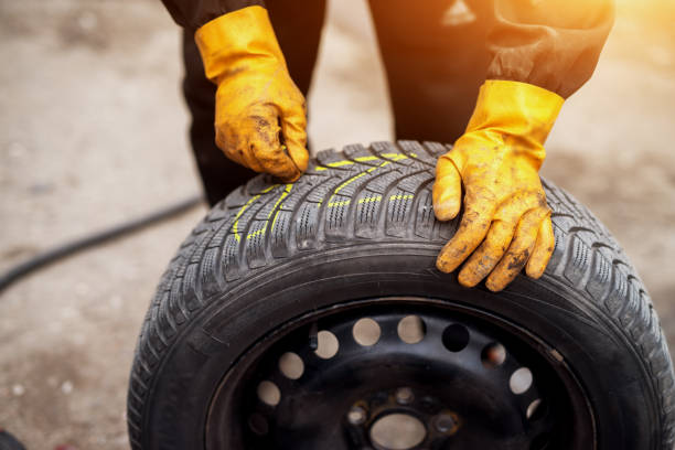 istock Mechanic with orange gloves is using chalk to mark tires while leaning on one in his workshop. 958472148