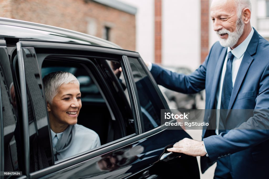 Senior caballero apertura de puerta de coche para la mujer de negocios maduros - Foto de stock de Puerta del coche libre de derechos