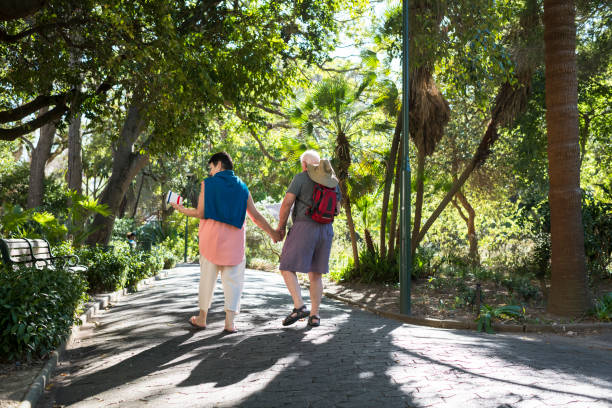 istock Happy senior couple walking on pathway in park 958473504