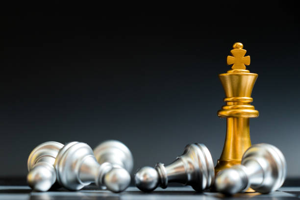 istock Gold king chess piece win over lying down pawn on black background 958476730