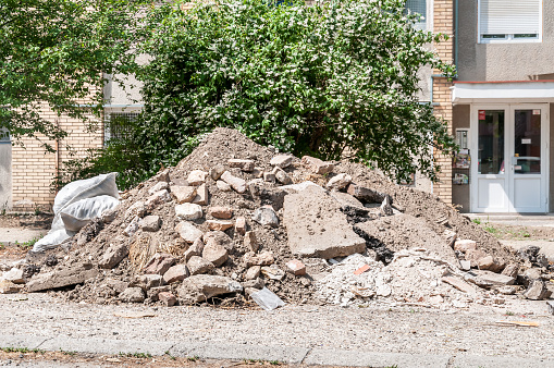 Big pile of cement concrete and dirt on the street in front of the residential building left as remains of the apartment renovation and reconstruction