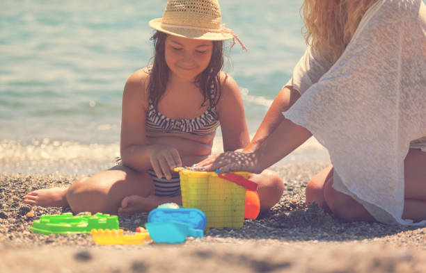istock Young Mother And Daughter Relaxing At The Beach 958479762