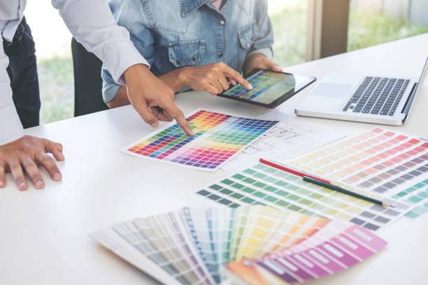 istock Young colleagues designers working together on a creative project and color samples for selection, Color swatch samples, Brainstorming Planning Partnership, creative graphic design working desktop 958492064