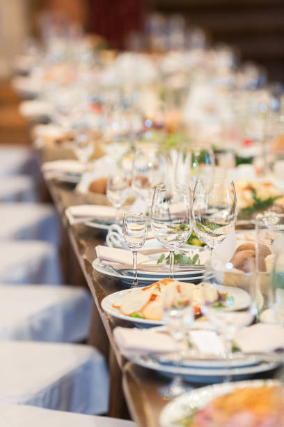 celebration, wedding, catering concept. there is a table covered with amount of plates and different glasses for various drinks, everything is prepared for guests stock photo