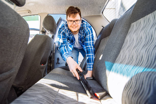 istock man cleaning inside car with vacuum cleaner. carwash concept 958497318