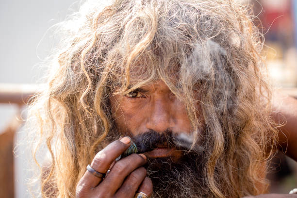 hindu sadhu rauchen ganja, marihuana, mit chillum auf den ghats des flusses ganges in varanasi, indien. nahaufnahme - hinduism outdoors horizontal close up stock-fotos und bilder