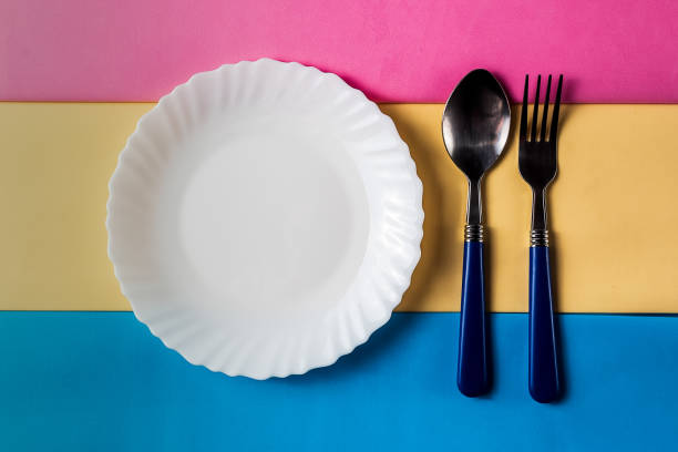 istock Still life of white empty plate with cutlery on colored background.; Minimalism style. 958504220