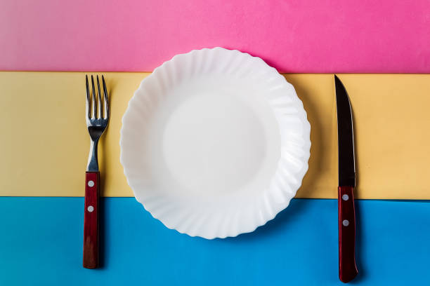 istock Still life of white empty plate with cutlery on colored background.; Minimalism style. 958504224