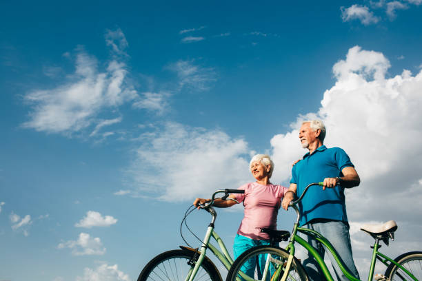 coppia matura che si gode la giornata in bicicletta - mature adult bicycle senior adult heterosexual couple foto e immagini stock