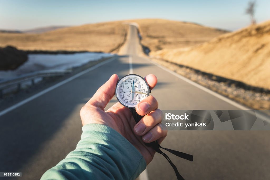 Compass in Hand mountain road background .Vintage Tone Compass in Hand mountain road background .Vintage Tone. Navigational Compass Stock Photo