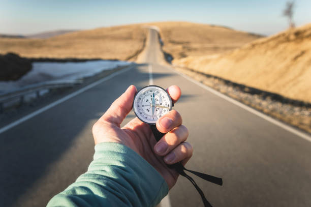 Compass in Hand mountain road background .Vintage Tone Compass in Hand mountain road background .Vintage Tone. west direction stock pictures, royalty-free photos & images