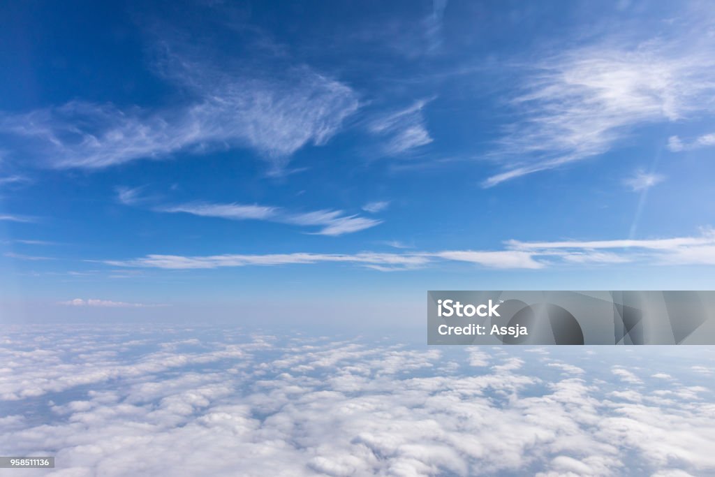 View from the airplane to the sky above the Alps mountains. Blue sky with clouds. Background. View from the airplane to the sky above the Alps mountains. Blue sky with clouds. Sky Stock Photo