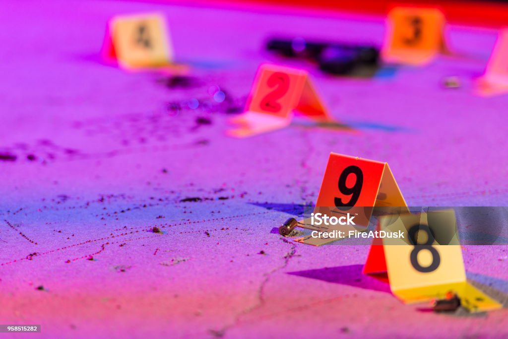 Shell Casing Evidence A shell casing is marked with an evidence marker within a crime scene. Crime Scene Stock Photo