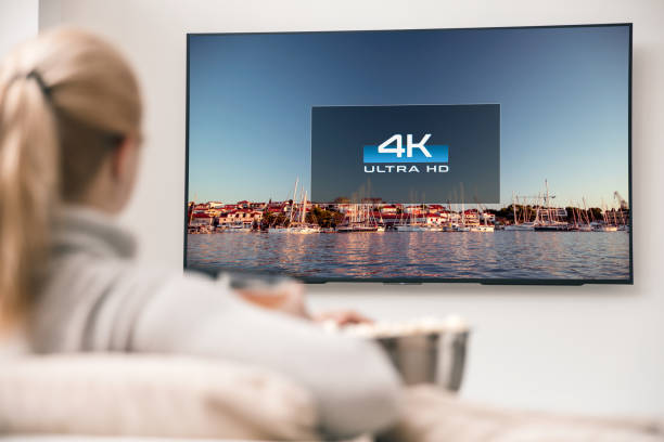 grande tv moderna con risoluzioni 4k e giovane donna in primo piano guardando alcuni video - risoluzione 4k foto e immagini stock