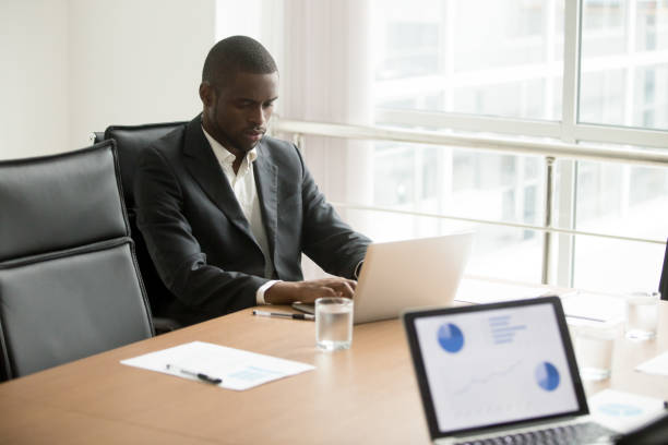 istock Serious african businessman working on laptop sitting at conference table 958531302