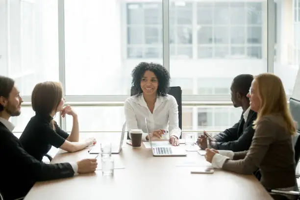 Photo of Smiling african american female boss leading corporate diverse team meeting