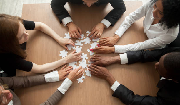 istock Multiracial group of colleagues engaging in assembling puzzle, top view 958531452