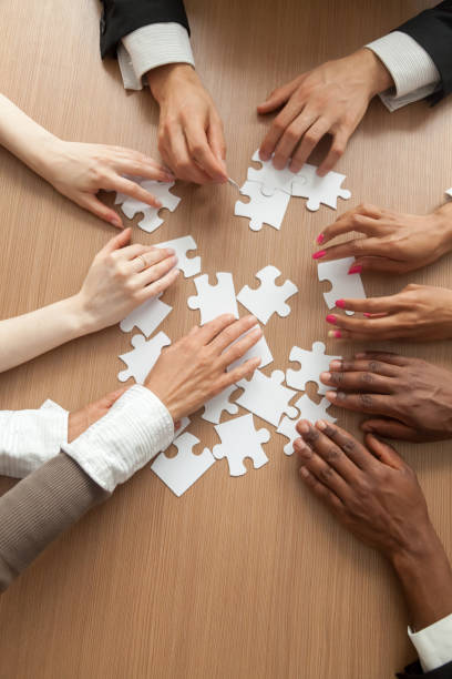 istock Multiracial business team assembling puzzle together, vertical close up view 958531462