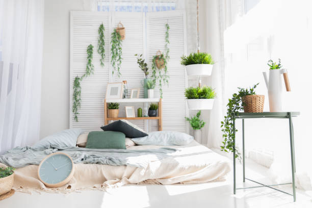 istock Light modern scandinavian bedroom interrior with bed, pillows, plaids, clock, shelves, green plants in baskets. Mock up morning pattern background. 958531722