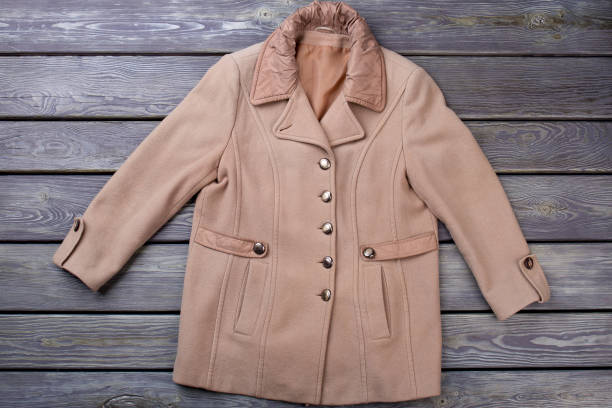 Female autumn topcoat, top view. Women soft cashmere overcoat on old wooden background. Feminine classy outerwear.