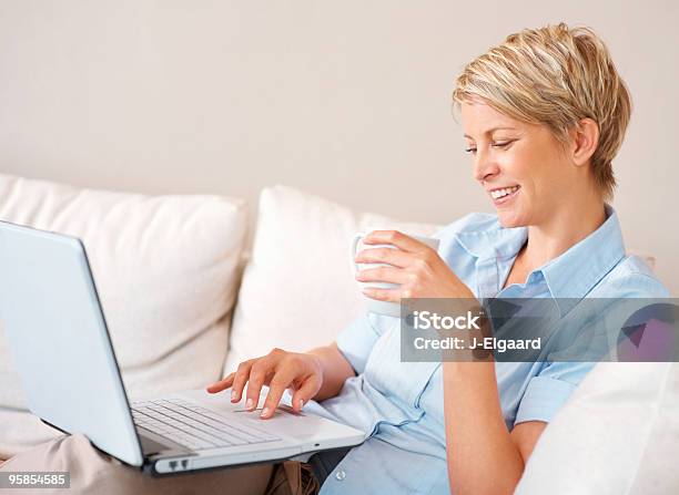 Mujer Trabajando En Su Computadora Portátil Mientras Disfruta De Un Café Foto de stock y más banco de imágenes de 30-34 años