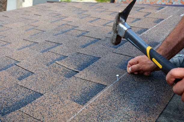 istock Contractor installing bitumen roof shingles with hammer and nails. 958546746