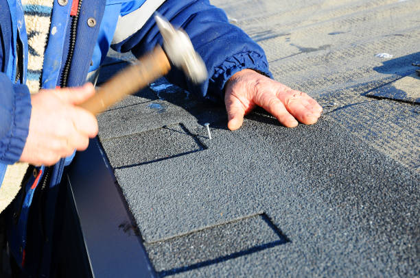 istock Worker hands installing bitumen roof shingles using hammer in nails. 958547030