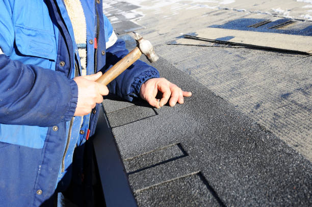 istock Worker hands installing bitumen roof shingles using hammer in nails. 958547040