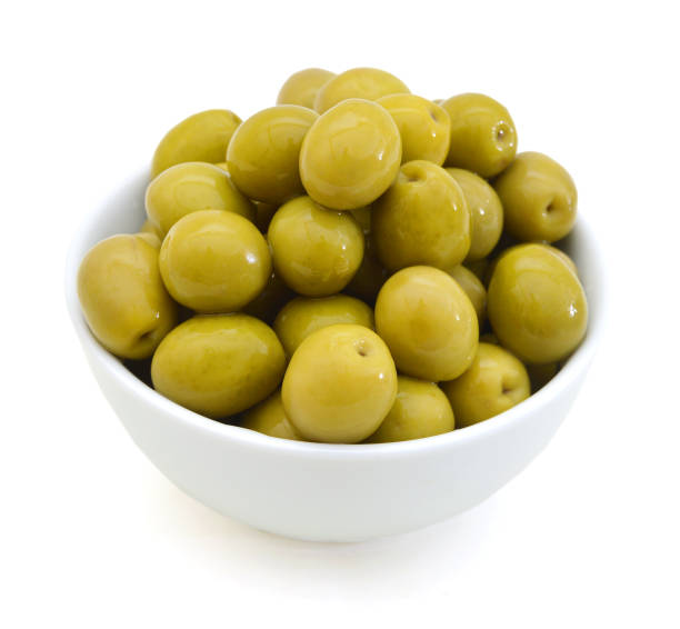 istock pickled green olives in a bowl and olive tree branch on a white background 958551570