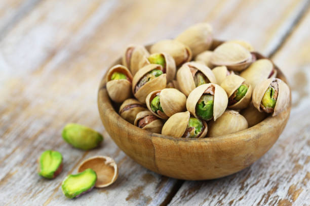 istock Pistachios with and without shell in bamboo bowl on rustic wooden surface 958551592