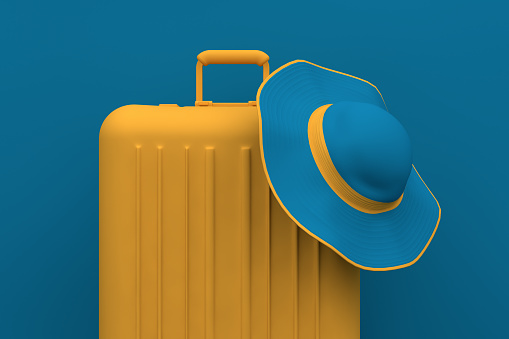 Minimal Summer travel concept, hat and suitcase on blue pastel background.