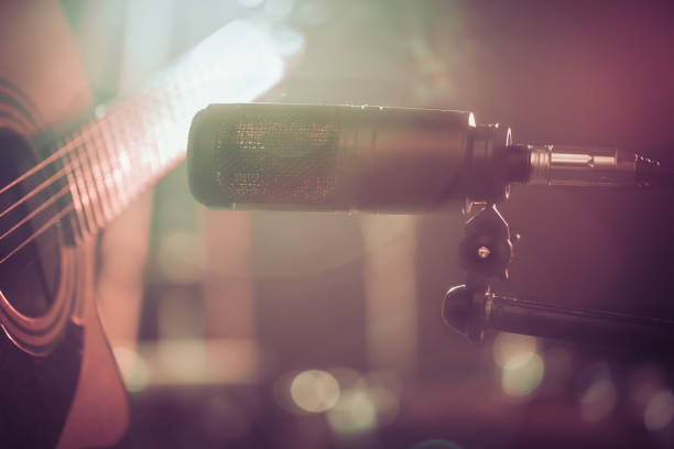 istock The Studio microphone records an acoustic guitar close-up. Beautiful blurred background of colored lanterns. 958552596