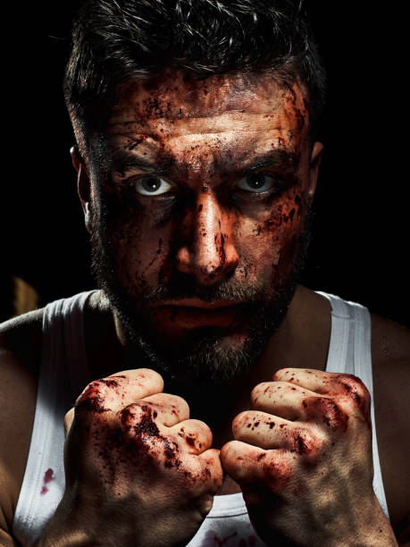 Portrait of a strong man with a beard, face in blood. He looks at the camera with different emotions. Blood and sweat dripping down his face. Fists erased from strikes