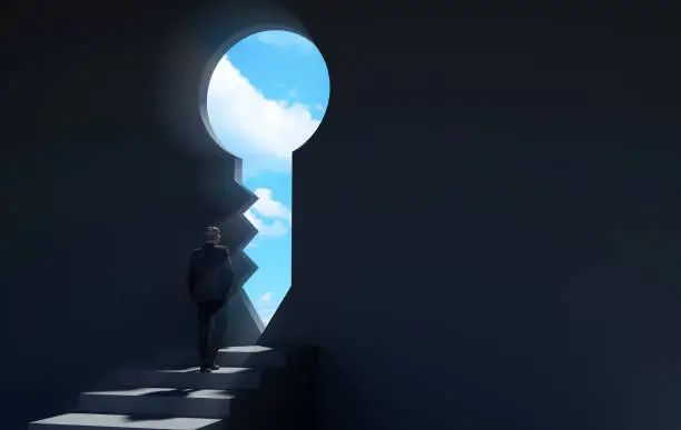 Photo of Businessman walking on stairway in dark room through key shaped door revealing blue sky for new opportunities
